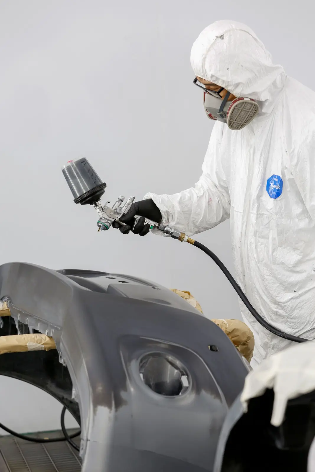 Technician applying coating inside a controlled paint booth